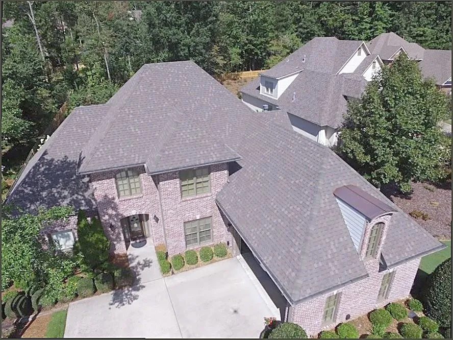 Aerial view of a finished hip roof on a large brick home in Dallas